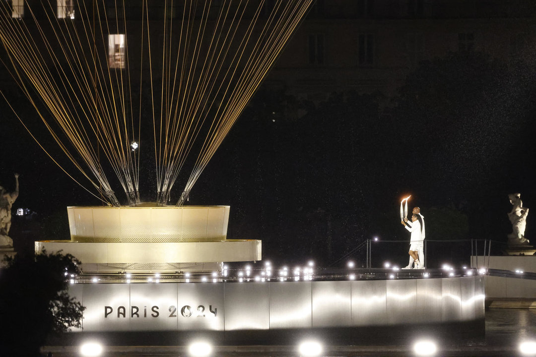 Los atletas galos Marie-Jose Perec (i) y Teddy Riner (d) se dirigen con la antorcha olímpica al pebetero durante la ceremonia de inauguración de los Juegos Olímpicos de París 2024, este viernes en la capital francesa. EFE/ Miguel Tona POOL