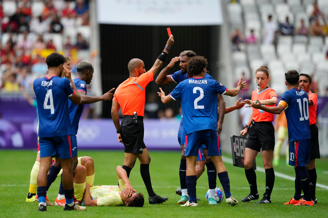 El árbitro Adel Al Naqbi (c) le saca la tarjeta roja al dominicano Edison Azcona (d) tras una acción contra Pau Cubarsí (en el suelo) durante el partido del Grupo C de fútbol masculino de los Juegos Olímpicos de París 2024 disputado en el Estadio de Burdeos. EFE/ M. Reino