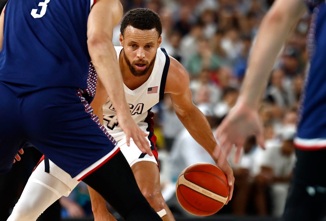 Stephen Curry (c), base de Estados Unidos, fue registrado este jueves, 8 de agosto, al intentar superar la marca de la defensa de Serbia, durante una de las semifinales del baloncesto de los Juegos Olímpicos 2024, en el coliseo South París Arena de la capital francesa. EFE/Yoan Valat