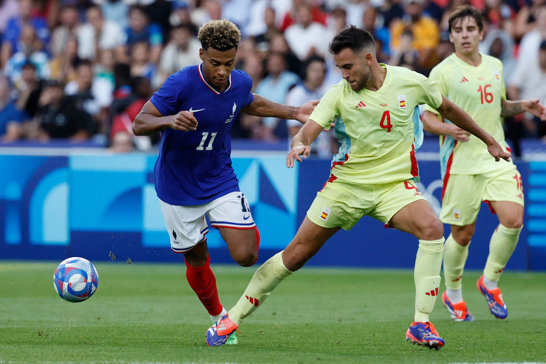 El jugador francés Desiré Doue (i) disputa un balón ante el jugador español Eric García durante la prorroga del partido por la medalla de oro de los Juegos Olímpicos de París 2024 que Francia y España disputan este viernes en el Parc des Princes, de Paris . EFE/ JUANJO MARTIN